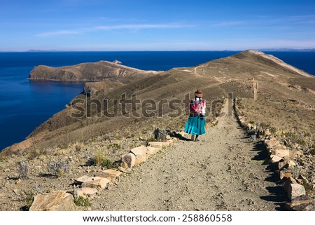 ISLA DEL SOL, LAKE TITICACA, BOLIVIA - NOVEMBER 7, 2014: Unidentified woman in traditional wear walking on path on November 7, 2014 on Isla del Sol (Island of the Sun), Lake Titicaca, Bolivia