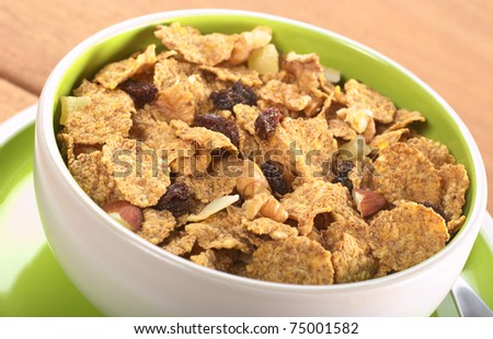 Wholewheat cereal with dried fruit, raisin, walnut and almond in bowl (Selective Focus, Focus in the middle of the bowl)