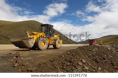 Earth movers in field with dust