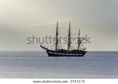 Tall ship anchored in a calm sea lit by morning light