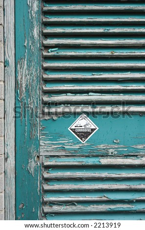 Tatty door with peeling paint and a warning sticker