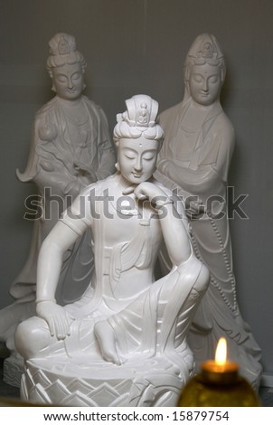Chinese buddhist female statues in thinking pose with candle flame