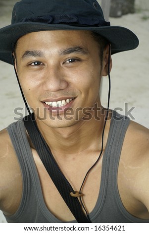 Happy smiling asian man with black hat at beach