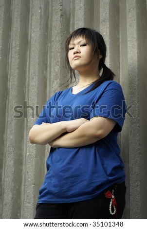 stock photo Rebellious asian teen girl leaning against wall