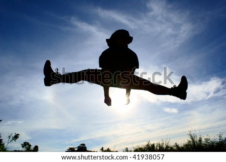Silhouette of person jumping and leg split in air with blue sky and clouds