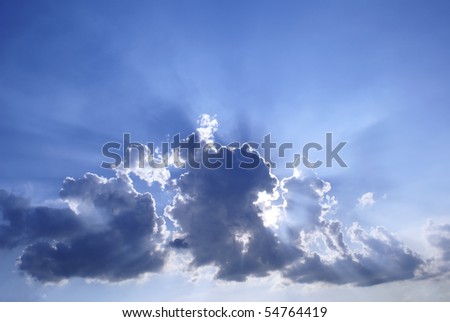 Blue cloudy sunburst sky with crepuscular sun rays streaming out from behind clouds