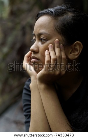stock photo Troubled asian teen girl thinking with hands on face