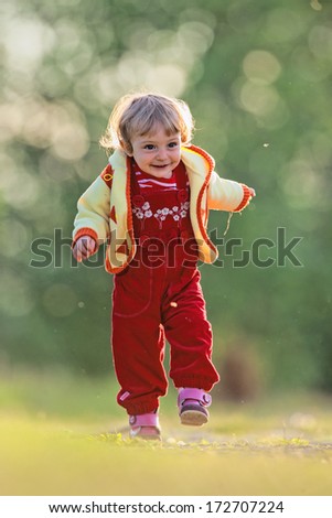 Happy  baby girl running at green  field. Active little girl running on a meadow