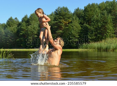 In the summer, bright sunny day, the little girl and man is bathed dives,run, jumps into the river. Beside him spray.