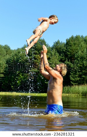 In the summer, bright sunny day, the little girl and man is bathed dives,run, jumps into the river. Beside him spray.