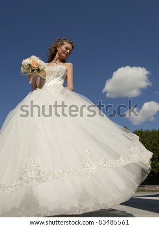The bride with a bouquet and the sky. The bride in a wedding dress with a bouquet with clouds.
