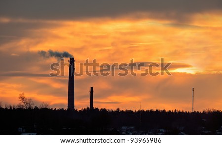 Smoking pipe against a sunset sky.  The smoke goes from pipes. Red Sunset Sky background