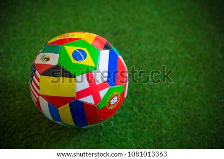 Close up view of a classic world flag football on lush green grass background. Unique, home-made football prop.