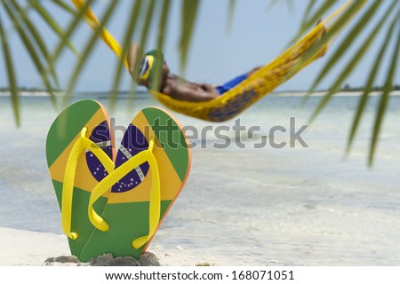 Man Relaxes In Hammock Over The Sea Leaving His Brazil Flag Flip Flops In The Sand