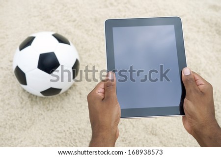 Football soccer sports ball with hands holding blank tablet technology on the beach in Rio de Janeiro Brazil