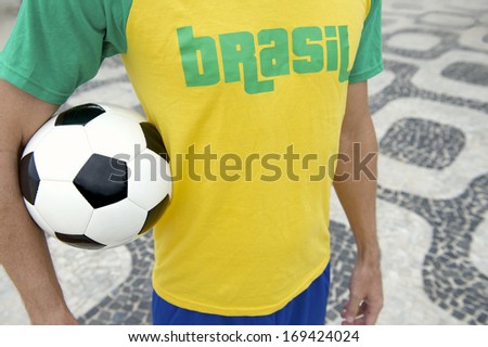 Brazilian soccer player holding football wearing Brasil shirt in Brazil colors Ipanema sidewalk Rio de Janeiro
