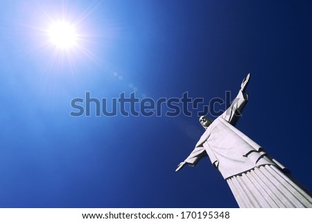 Corcovado Christ the Redeemer statue standing under the rays of bright tropical sun blue sky Rio de Janeiro Brazil