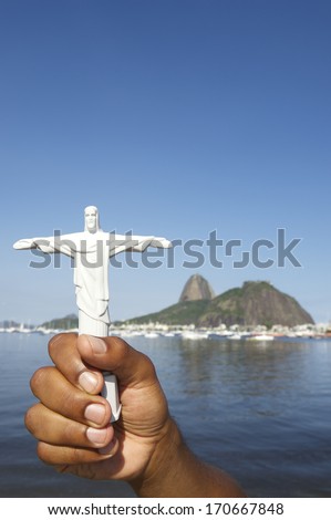 Brazilian holding Corcovado Christ the Redeemer statue souvenir at sunny view of Sugarloaf Mountain Rio de Janeiro skyline Brazil