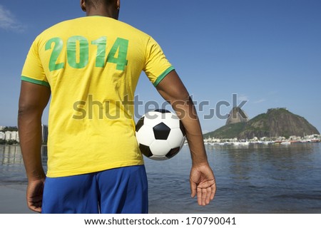 Brazilian soccer player holding football wearing 2014 shirt in Brazil colors at Sugarloaf Pao de Acucar in Rio de Janeiro