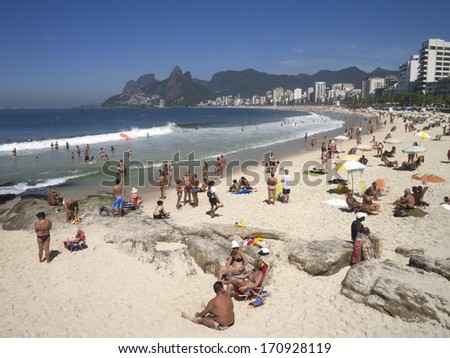 IPANEMA BEACH, RIO DE JANEIRO - OCTOBER 20, 2013: Residents of Rio relax at Arpoador, with the rest of Ipanema Beach stretching off into the horizon.