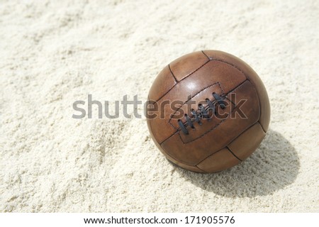 Vintage brown football soccer ball sits on sand beach background in Rio de Janeiro Brazil