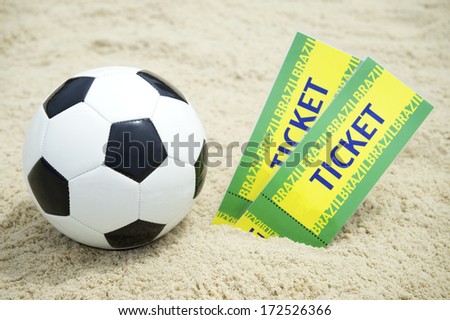 Two tickets to football event stand on Brazilian beach with soccer ball