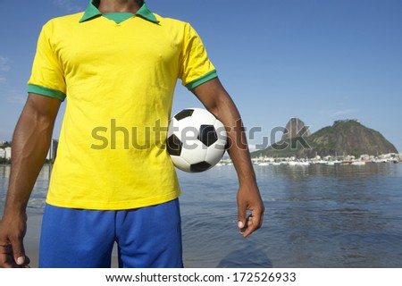 Brazilian soccer player holding football wearing shirt in Brazil colors at Sugarloaf Pao de Acucar in Rio de Janeiro