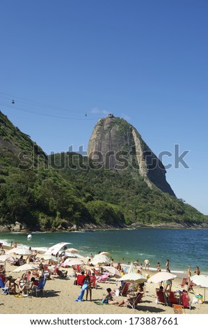 URCA, RIO DE JANEIRO - OCTOBER 20, 2013: Local residents and tourists relax at Praia Vermelha beach against a backdrop of Sugarloaf Mountain, one of the most popular tourist attractions in the city.