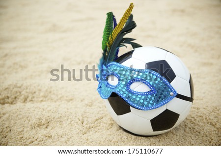 Football soccer ball wearing blue Brazilian carnival mask on beach in Rio de Janeiro