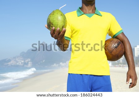 Brazilian soccer player in Brazil colors holding vintage brown football and drinking coconut Rio de Janeiro