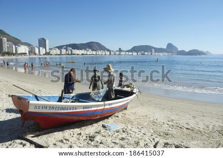 RIO DE JANEIRO, BRAZIL - FEBRUARY 3, 2014: Brazilian fishermen work from a brightly painted boat on a tranquil morning on Copacabana Beach.