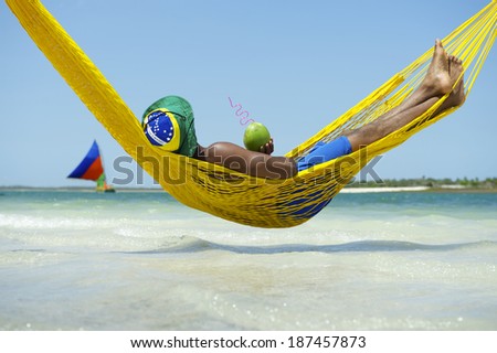 Brazilian man relaxing in beach hammock drinking fresh coconut water coco gelado