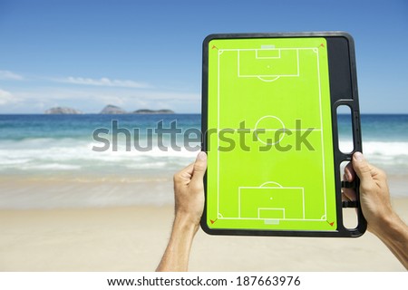 Hands holding football tactics board on empty beach at Ipanema Rio de Janeiro Brazil