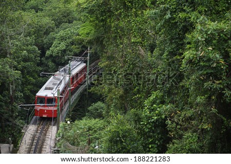 Red Brazilian train travels through thick green jungle at Tijuca National Forest in Rio de Janeiro Brazil