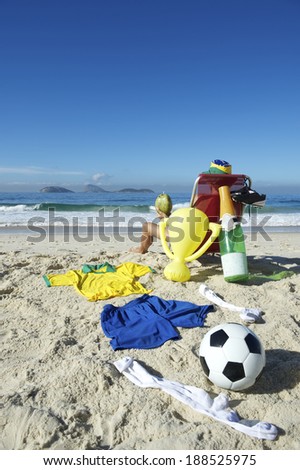 Champion Brazilian football player celebrating by relaxing in beach chair with soccer ball, champagne bottle, and trophy