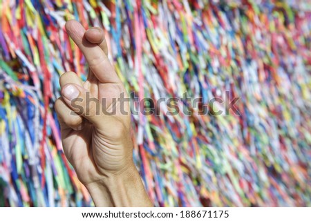 Brazilian hand fingers crossed for luck in front of colorful religious Brazilian wish ribbons fita do Bonfim in Salvador Bahia Brazil