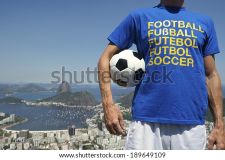 Soccer fan holding football wearing international shirt at bright sunny Rio de Janeiro skyline with Sugarloaf Pao de Acucar Mountain