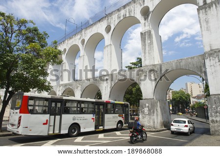 RIO DE JANEIRO, BRAZIL - FEBRUARY 13, 2014: A public bus passes alongside other traffic through the weathered arches of Arcos da Lapa Arches in Centro.