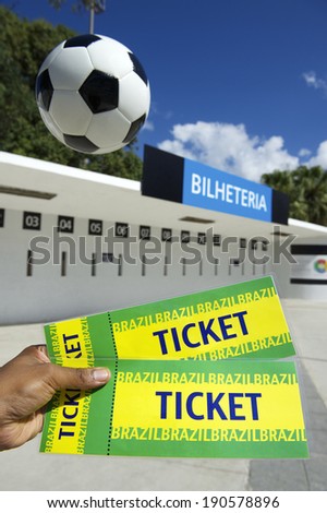 Brazilian soccer fan holding two Brazil tickets outside the stadium ticket window with football