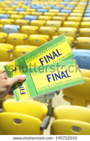 Soccer fan holding two Brazil final tickets in front of empty football stadium seats