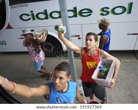 BOM DESPACHO, BRAZIL - JANUARY 9, 2013: Vendors selling drinks approach a long distance bus parked at the station.