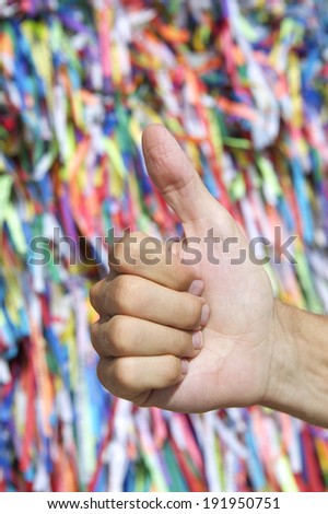 Brazilian thumbs up hand in front of colorful religious Brazilian wish ribbons fita do Bonfim in Salvador Bahia Brazil