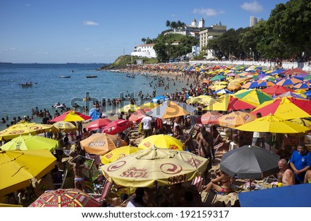 SALVADOR, BRAZIL - NOVEMBER 13, 2013: City residents relax with colorful beach umbrellas on a bright afternoon on Porto da Barra beach summer afternoon.