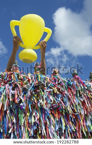 Hands holding good luck championship trophy at wall of Brazilian wish ribbons at the Bonfim church in Salvador Bahia Brazil