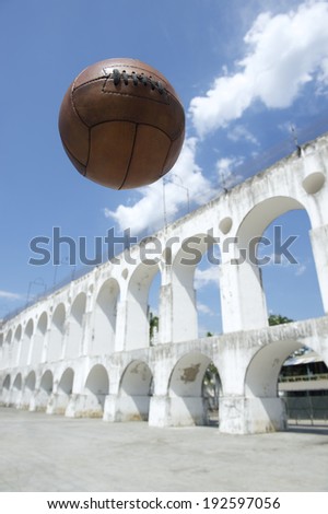 Vintage brown soccer ball football flying in the sky at Arcos da Lapa Arches Rio de Janeiro Brazil