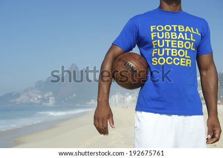 Brazilian soccer player in multi language message t-shirt holding vintage football Ipanema Beach Rio de Janeiro Brazil