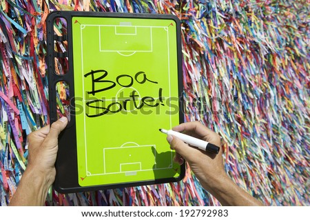 Hands writing Boa Sorte Good Luck message on football tactics board in front of Brazilian wish ribbons in Salvador Bahia Brazil