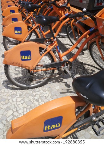 RIO DE JANEIRO, BRAZIL - MARCH 8, 2014: Row of orange bike share bicycles parked in a rack sponsored by Brazilian bank Itau.