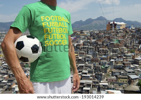 Brazilian man standing in international football t-shirt holding soccer ball in front of favela slum background in Rio de Janeiro Brazil