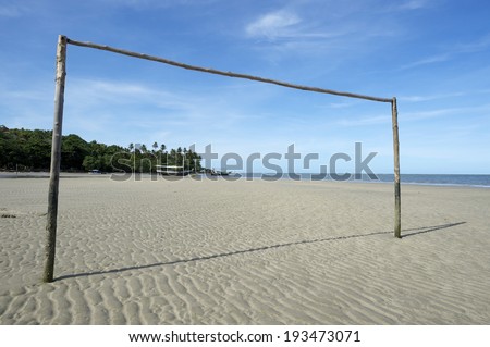 Simple empty Brazilian beach football pitch with rustic goal posts sticking out of the sand in Nordeste Bahia